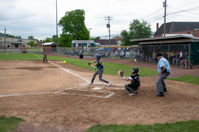 Umpire, catcher, and batter who is mid-swing about to hit the ball.