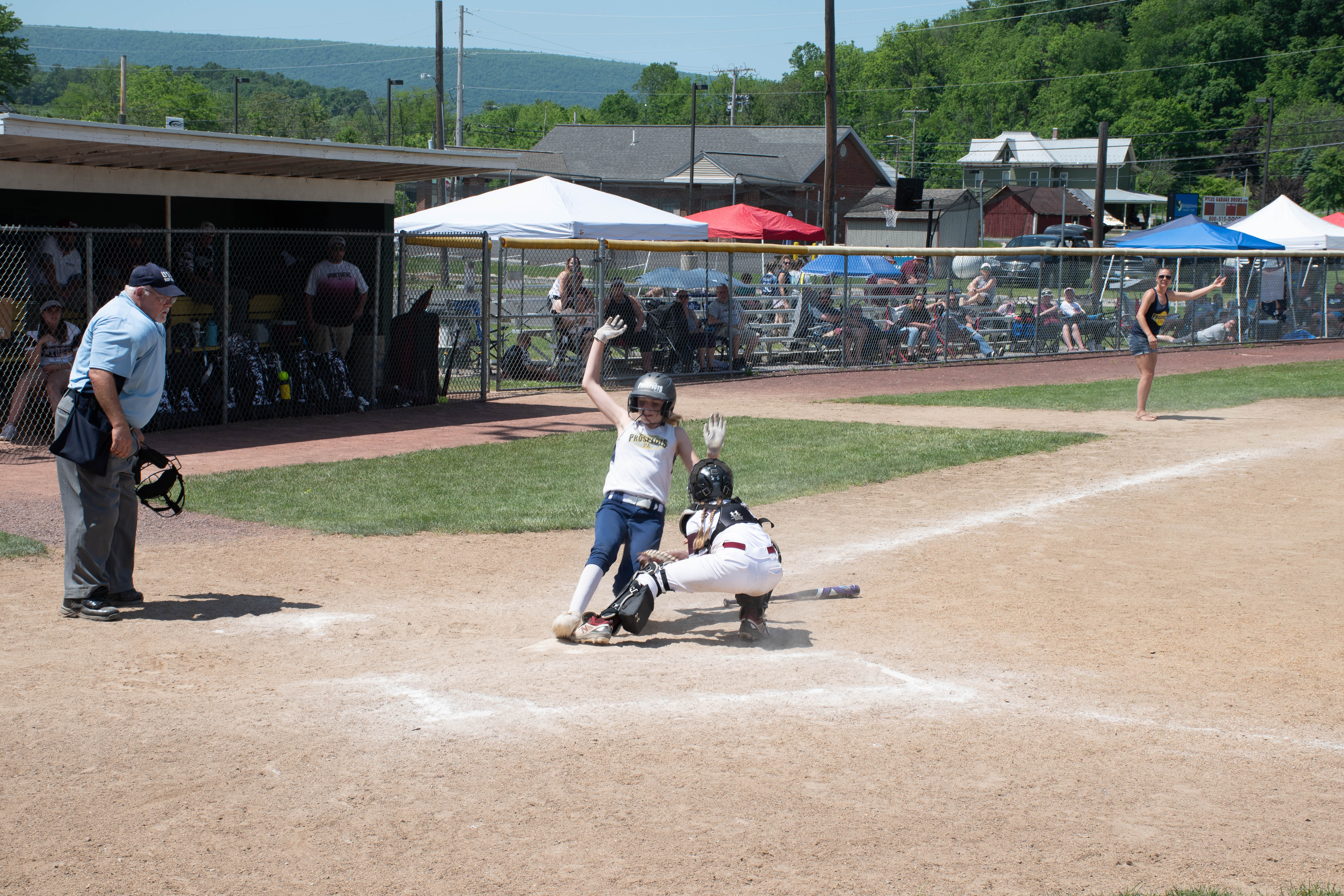 Umpire watching catcher and runner sliding into home plate.