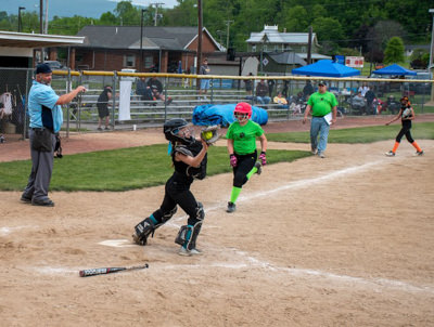 Catcher standing on home plate catching the ball just before runner reaches home.