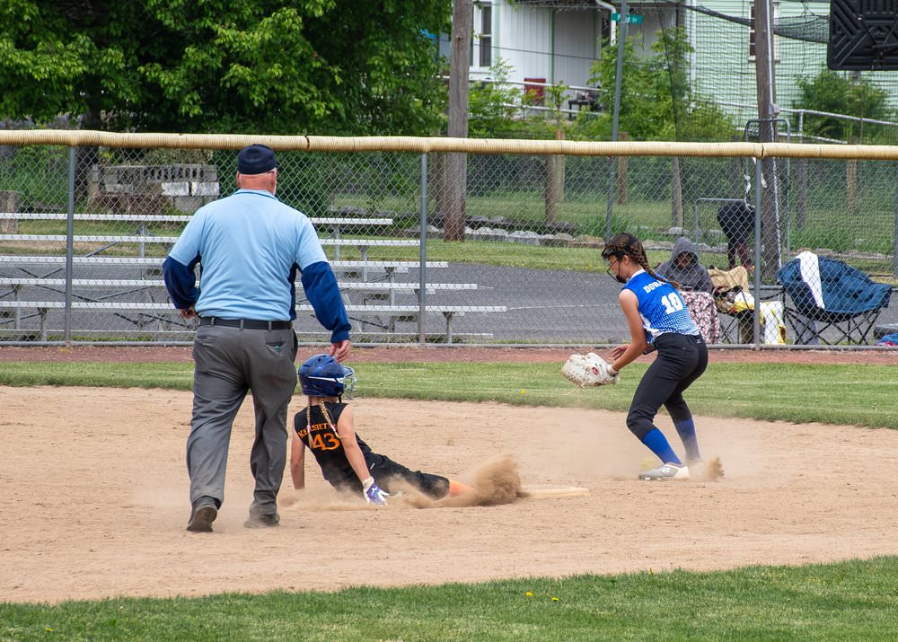 Umpire watching runner slide into second base as shortstop catches ball to the side.