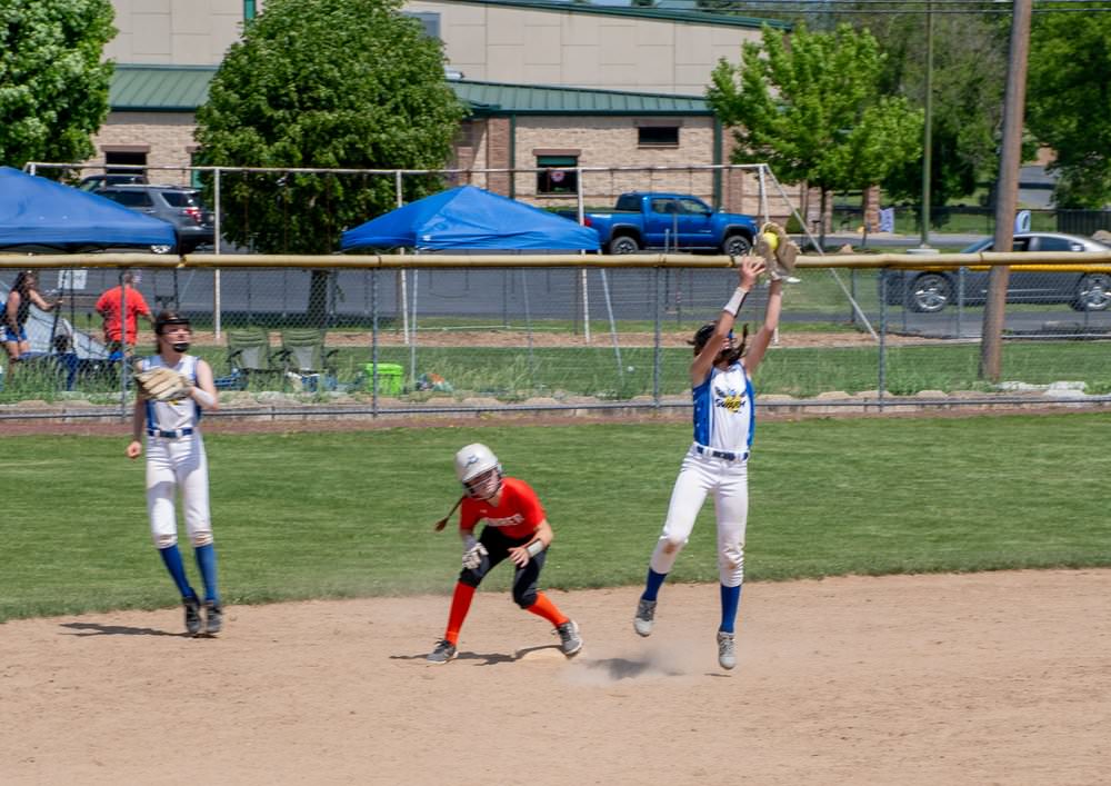 Thirdbaseman jumps to catch ball as runner steps onto third base.