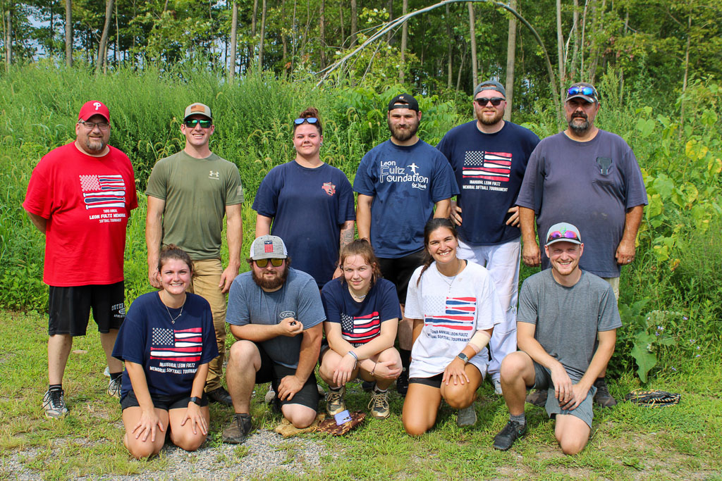 Another team posing in front of some shrubbery.