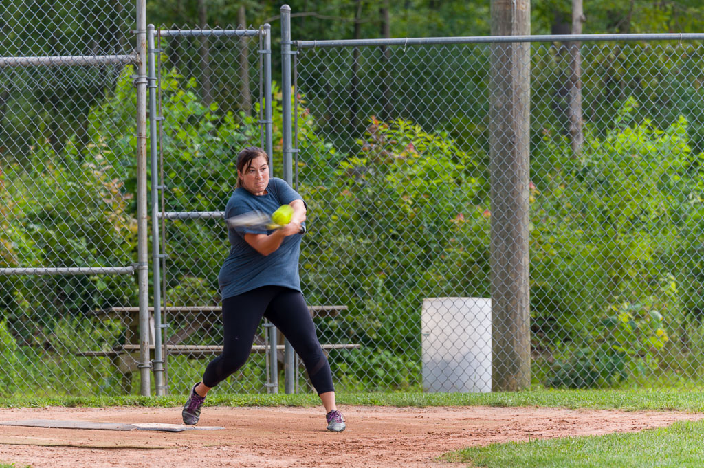 Batter in mid-swing as she hits the ball.