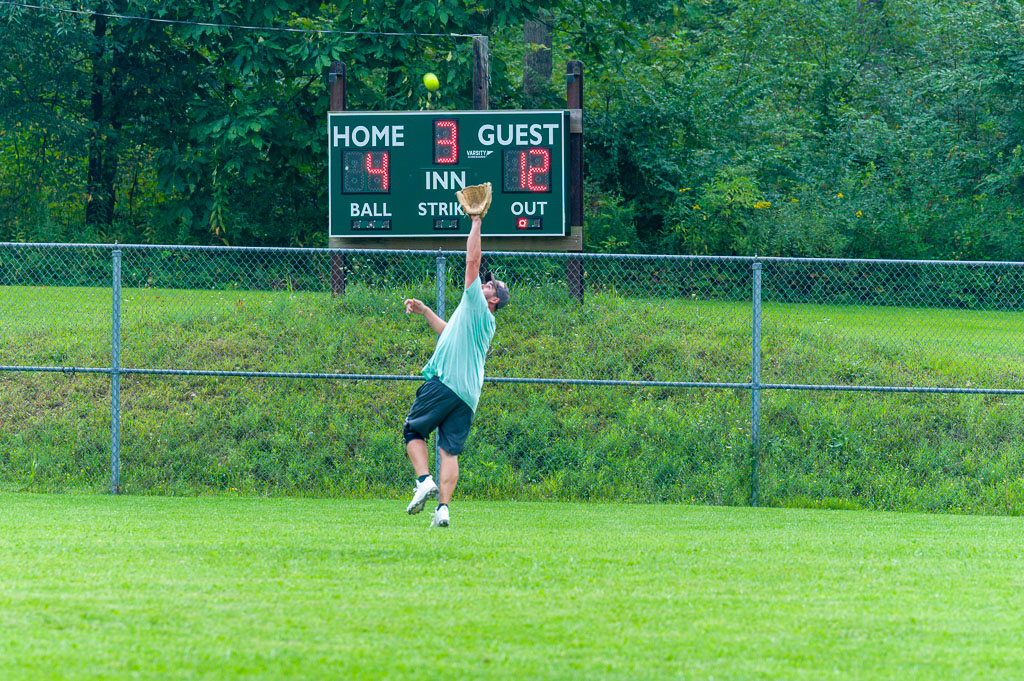 Outfielder jumps to catch fly ball.