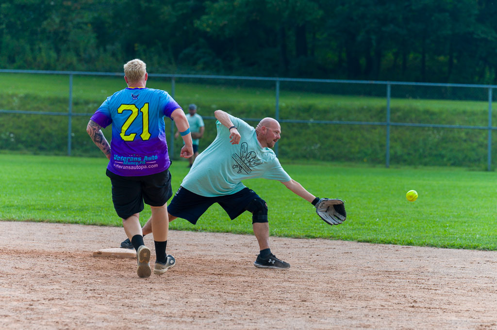 Second baseman stretches to catch ball as runner approaches.