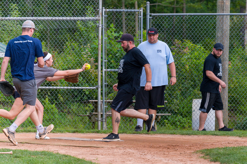 Catcher stretches to tag out runner as he crosses home plate.