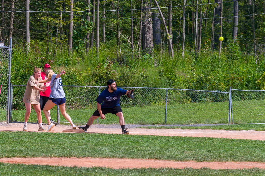 Catcher at home plate about to catch ball as runner crosses home.