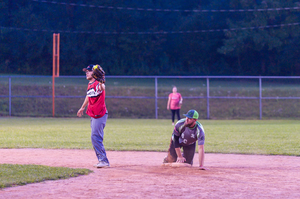 Second baseman catches ball as runner slides into second base behind him.