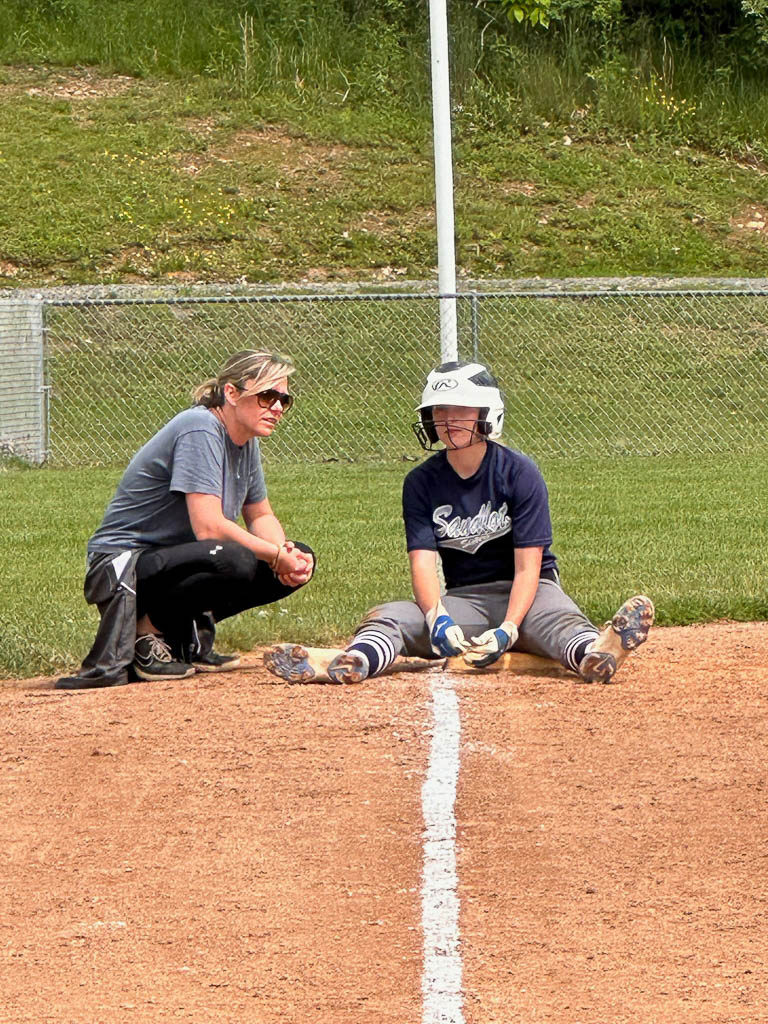 Coach talking to player resting on third base.