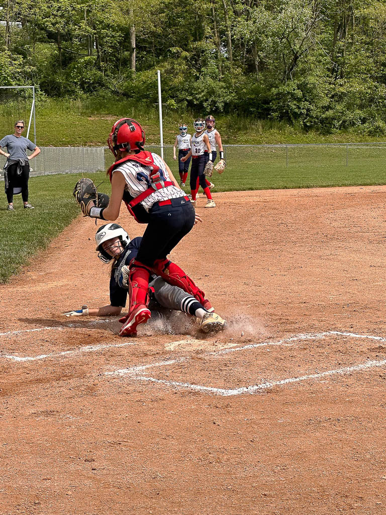 Runner sliding into home plate under catcher.