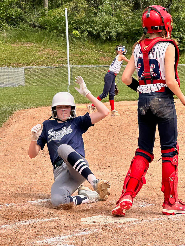 Runner sliding into home plate as catcher waits for ball.