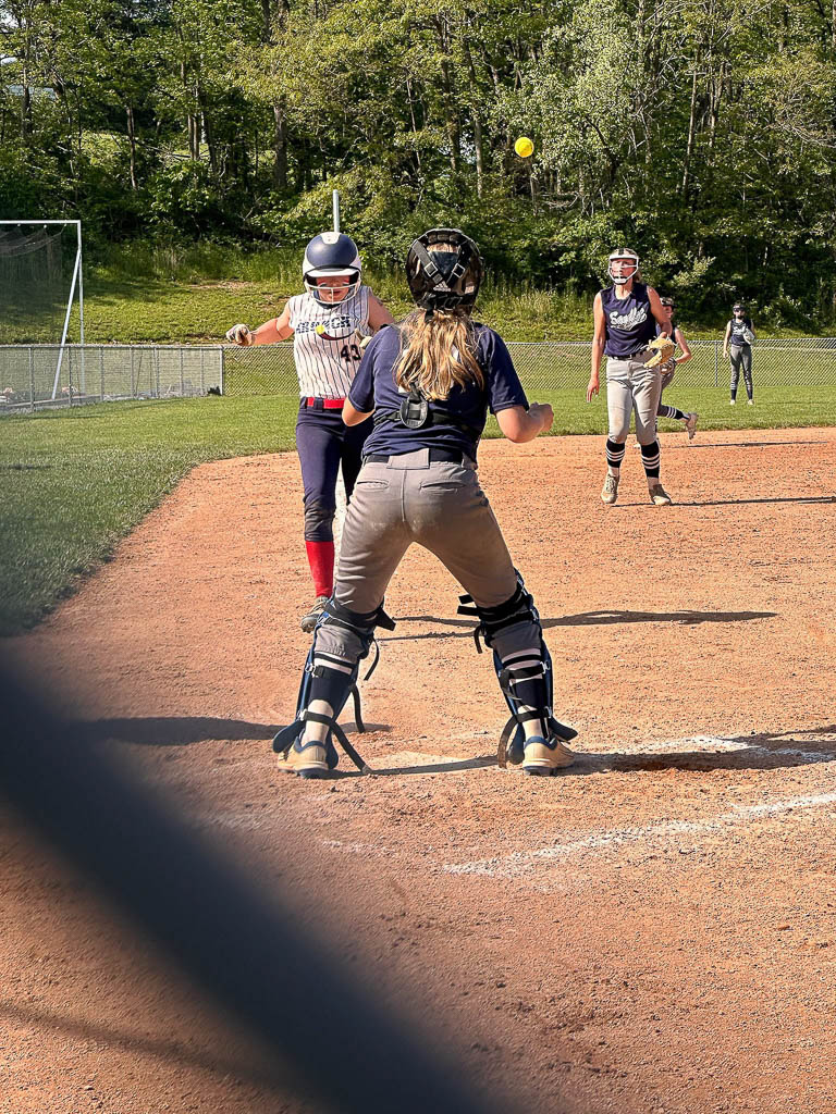 Runner heads for home as catcher prepares to catch the ball.