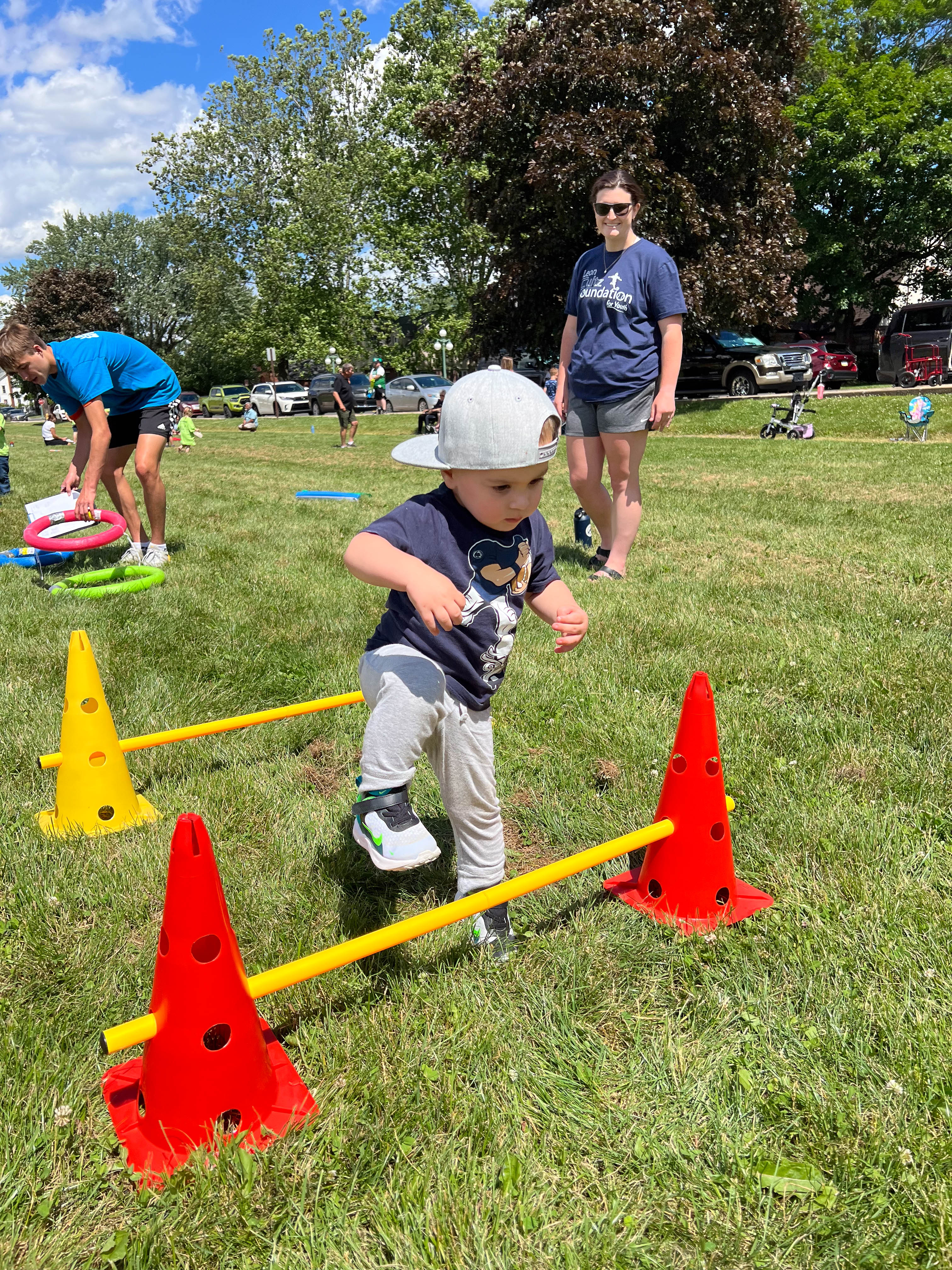 A young boy is stepping over the hurdles.